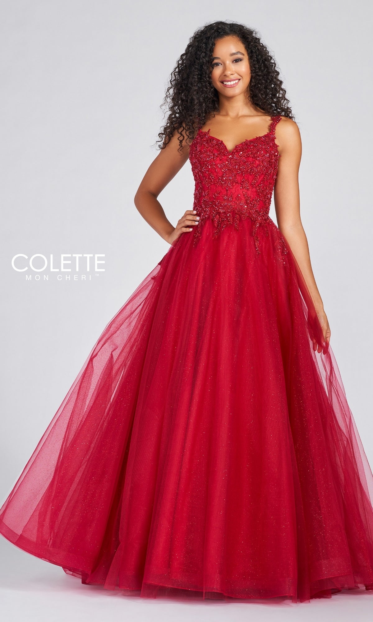 A woman stands against a plain background wearing the Glitter Tulle Prom Dress with Beaded Lace Bodice—a sleeveless, floor-length red gown featuring a fitted lace bodice and shimmering tulle skirt.